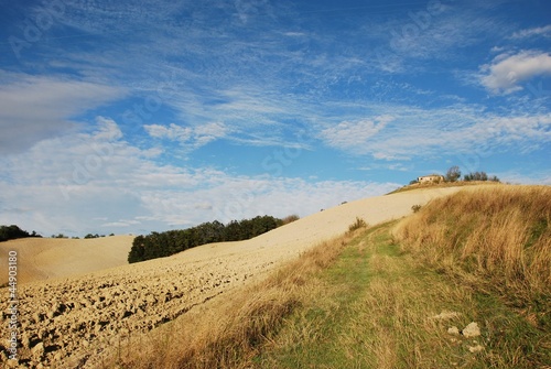 rudere nella campagna toscana con cielo azzurro e nubi