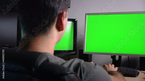 Man working in the office in front of green monitors