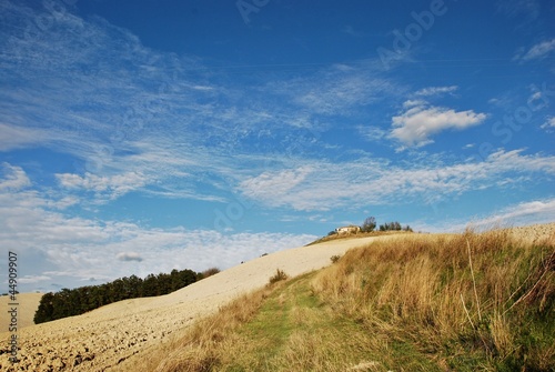 rudere nella campagna toscana con cielo azzurro e nubi