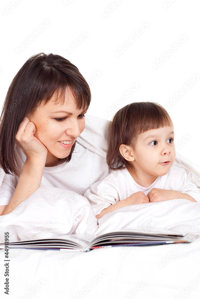 A beautiful Caucasian mother with her daughter lying with a book A beautiful Caucasian mother with her daughter lying with a book
