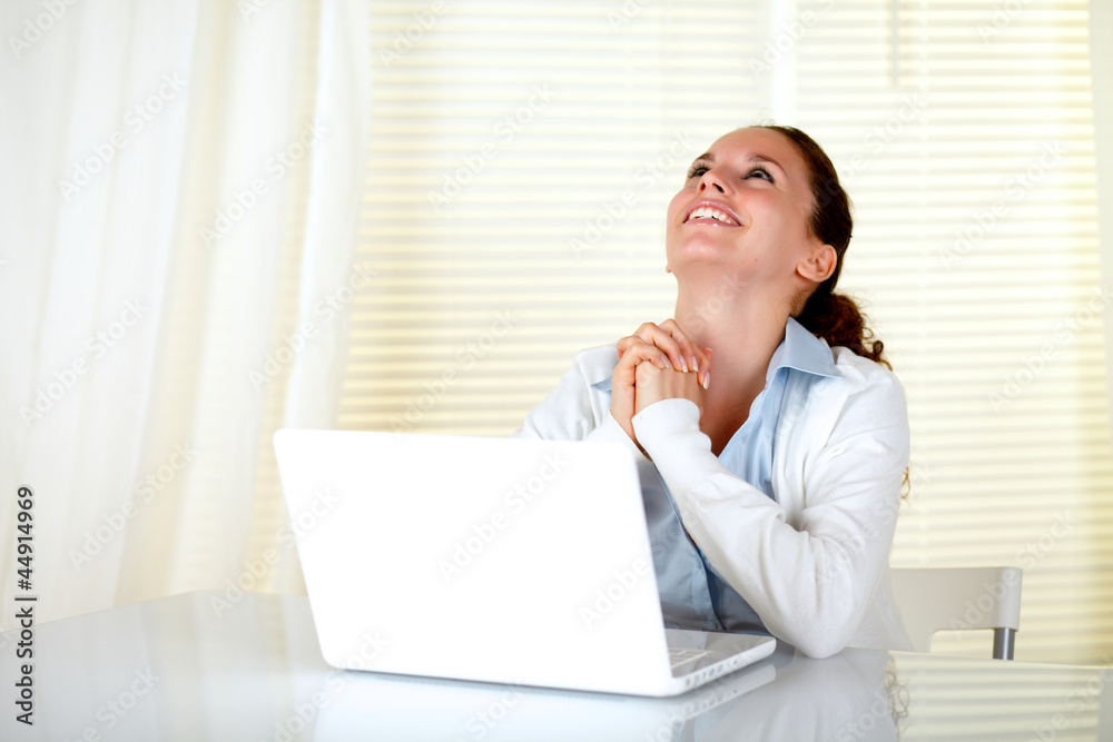 Happy woman working on laptop and looking up Happy woman working on laptop and looking up