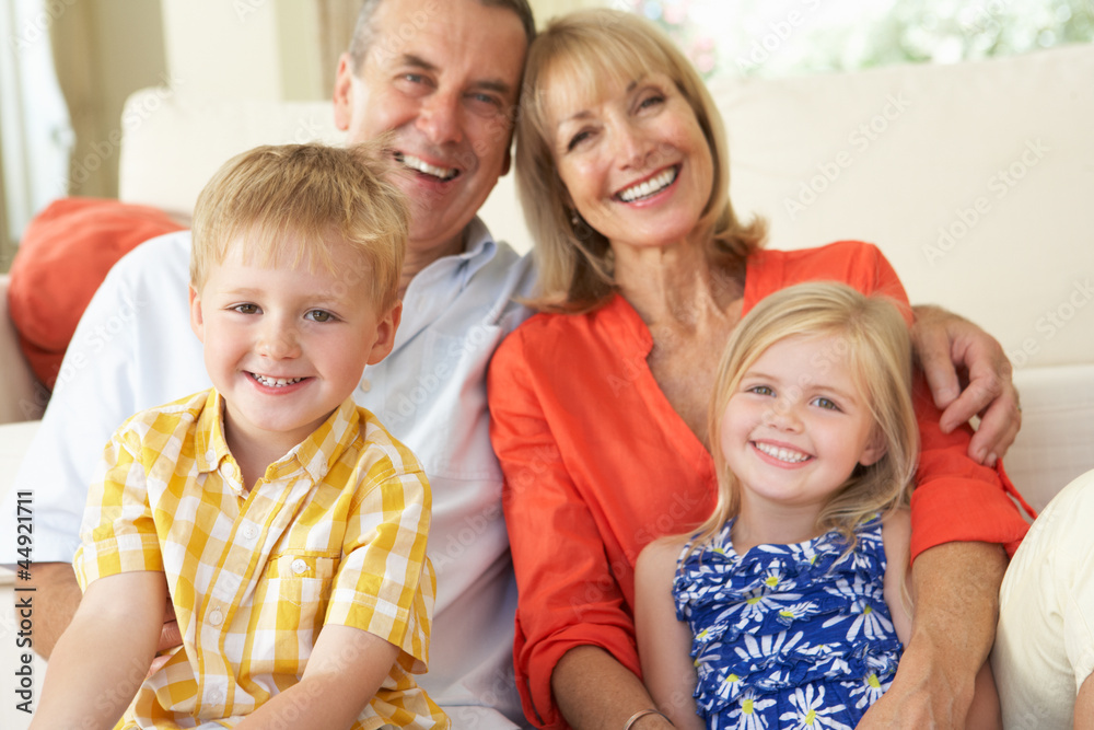 Grandparents With Grandchildren Relaxing On Sofa At Home Grandparents With Grandchildren Relaxing On Sofa At Home