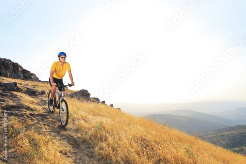 Fototapeta Naklejka Na Ścianę i Meble -  A young male riding a mountain bike on a sunset