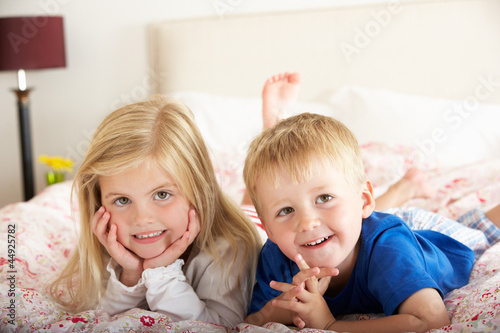 Two Children Relaxing On Bed