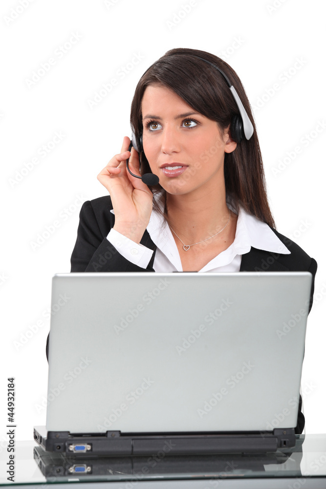 Woman wearing telephone in front of laptop computer Woman wearing telephone in front of laptop computer