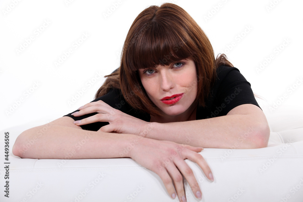 Gorgeous brown-haired woman leaning on a couch