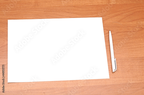 Blank sheet of paper with pen on wooden background