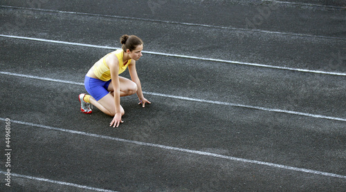 Athletic teenage girl in start position on track . © denys_kuvaiev