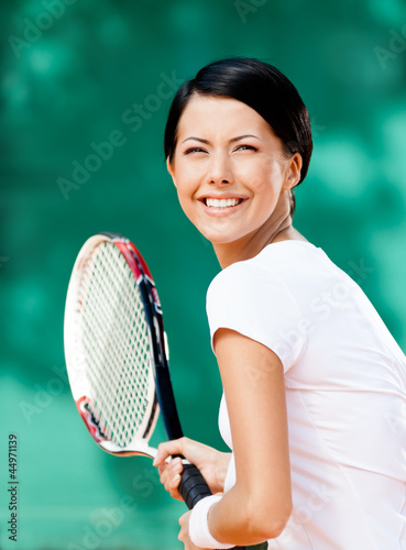 Portrait of pretty tennis player with racket at the tennis court