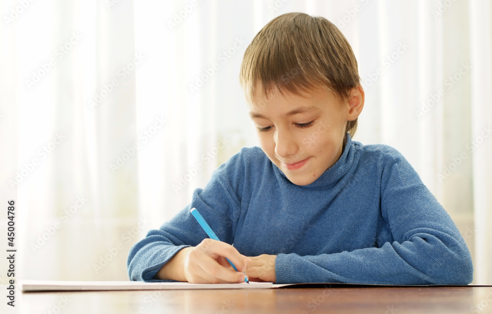 Beautiful teenager sitting at the table draws Beautiful teenager sitting at the table draws