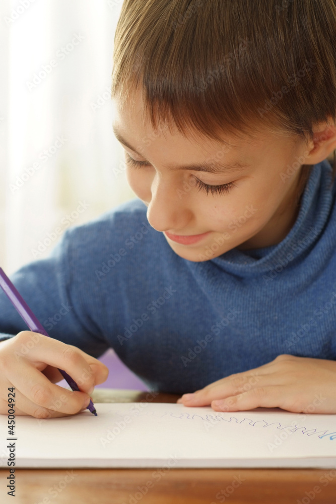 Pretty Caucasian teenager sitting at the table draws Pretty Caucasian teenager sitting at the table draws