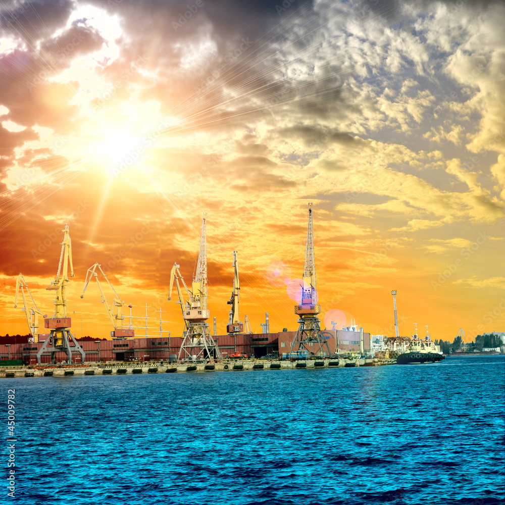 Silhouette of portal cranes in harbor aver the sunset