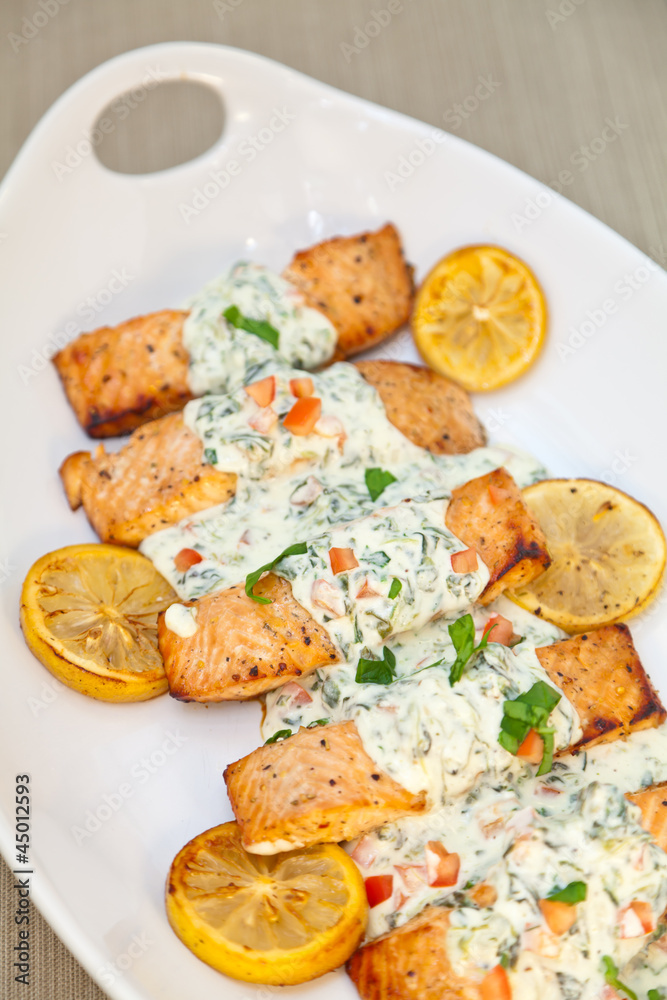 Cooked salmon fillets with spinach sauce on white plate Cooked salmon fillets with spinach sauce on white plate