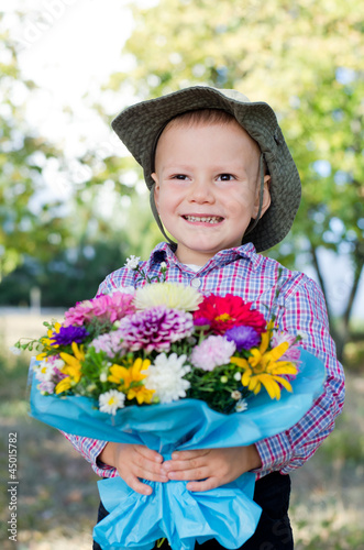 Grinning young boy with flowers