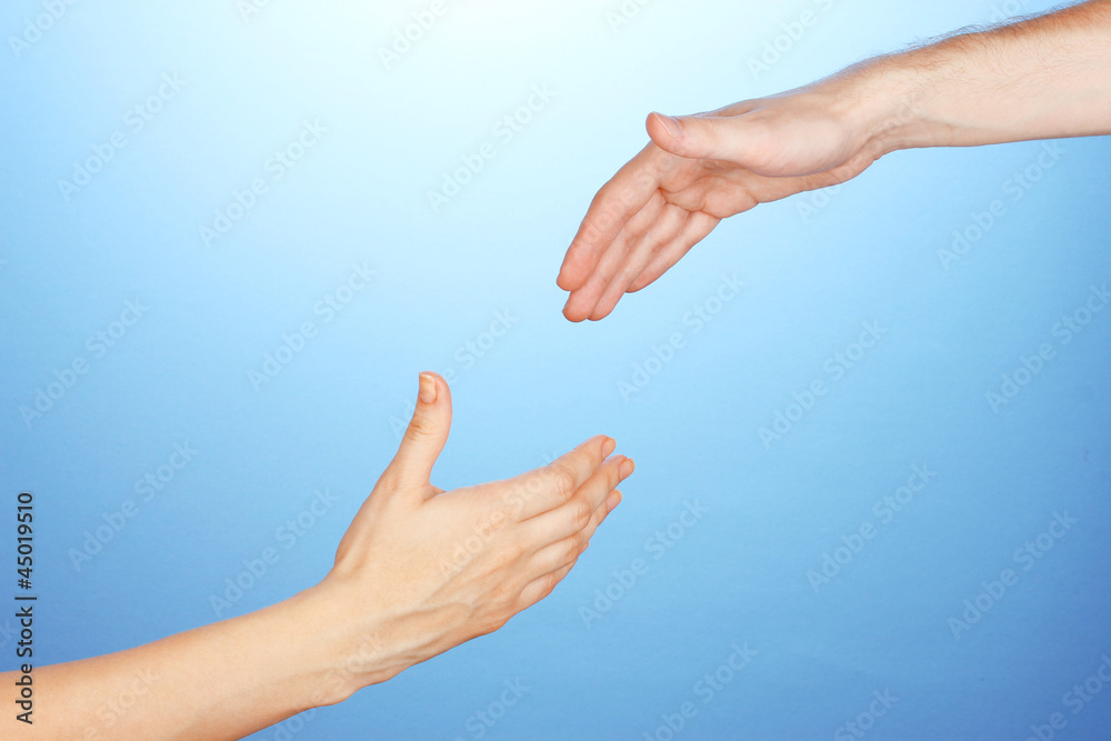 Women's hand goes to the man's hand on blue background