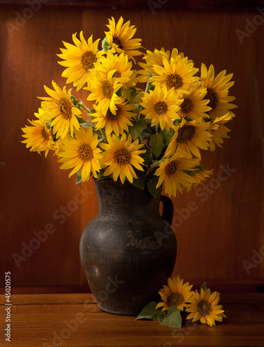 Fototapeta Naklejka Na Ścianę i Meble -  Beautiful Sunflowers in  old clay pot against a wooden wall