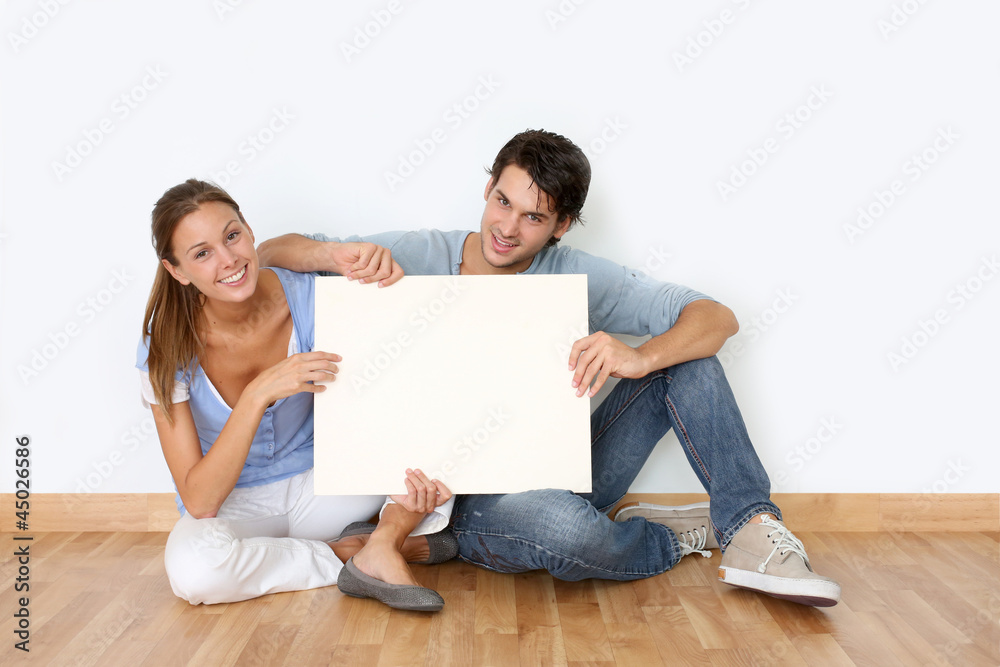 Couple sitting on the floor with message board Couple sitting on the floor with message board