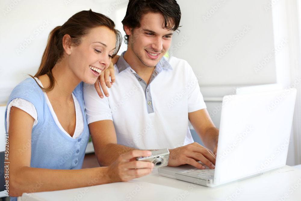 Couple at home uploading photographies on internet Couple at home uploading photographies on internet