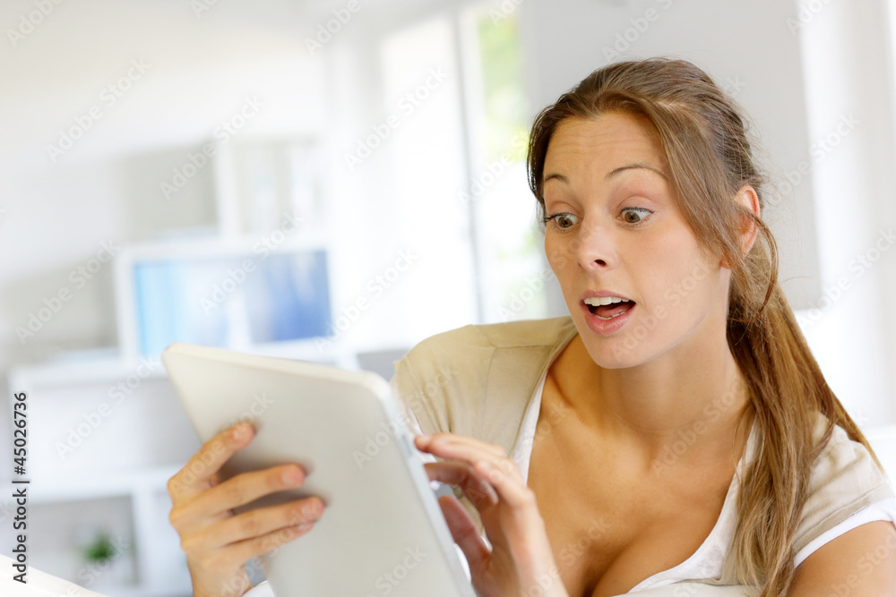 Surprised woman using digital tablet at home Surprised woman using digital tablet at home