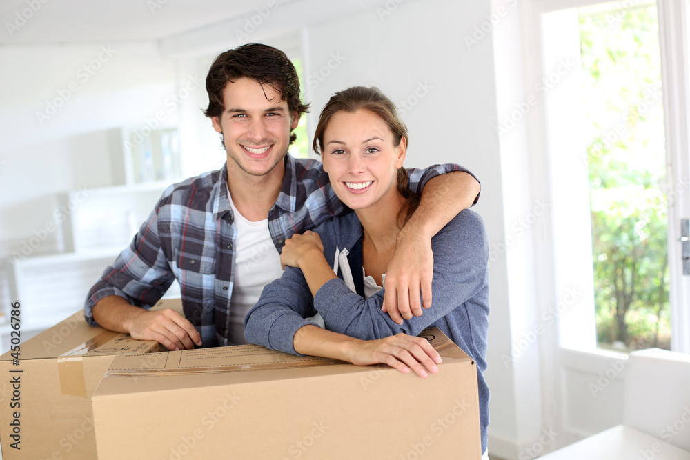 Smiling couple leaning on boxes in new home Smiling couple leaning on boxes in new home