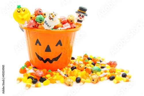 Jack-o-lantern candy pail with a pile of Halloween candy photo