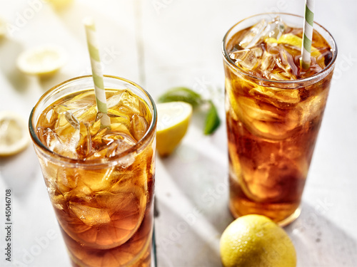 cold iced tea with straws and lemon slices in summer sun.