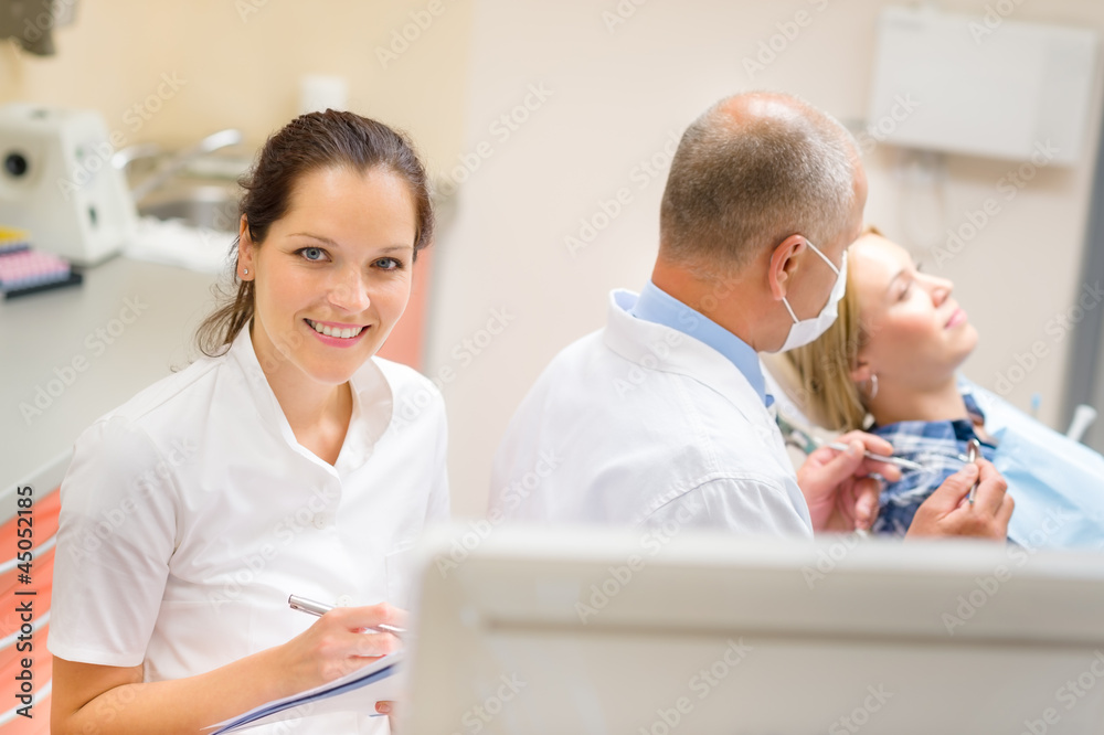 Obraz premium Smiling dental nurse prepare patient paperwork