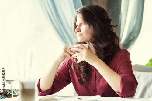 A woman in a restaurant is drinking coffee photo