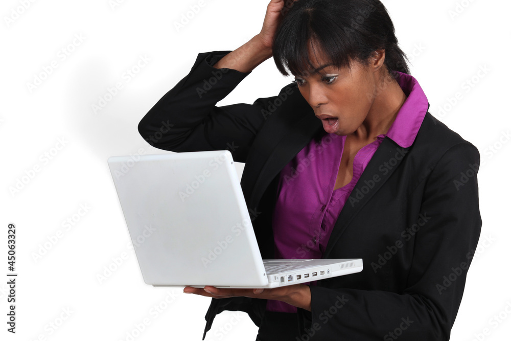 Woman looking in shock at her laptop Woman looking in shock at her laptop