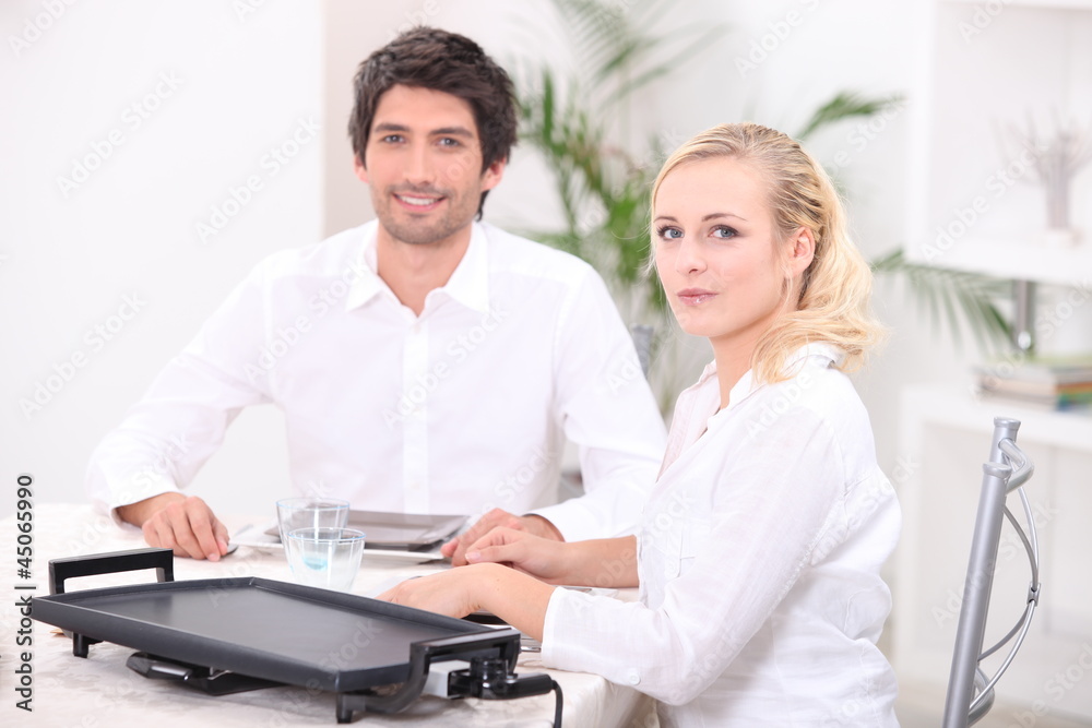 Couple using an electric tabletop hotplate Couple using an electric tabletop hotplate