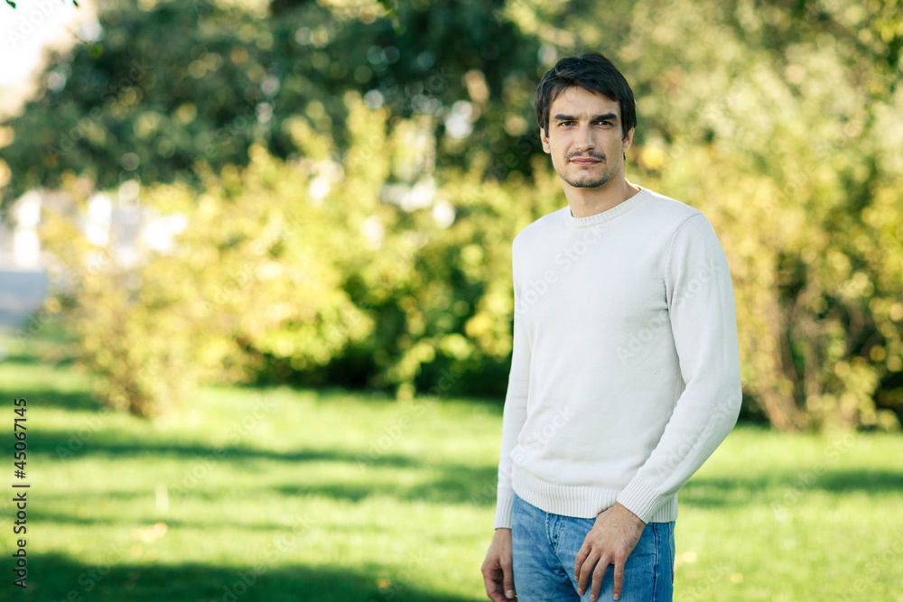Young man standing over green autumn background Young man standing over green autumn background
