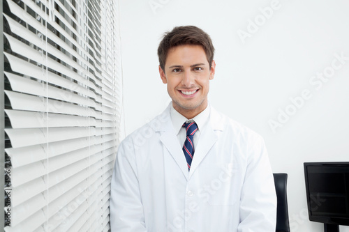 Foto Happy Dentist Standing In Clinic