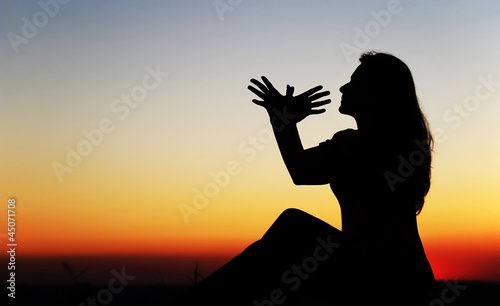 Girl at sunset, hands symbolize the bird