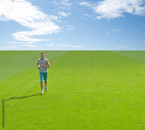 Sporty young man running on green field
