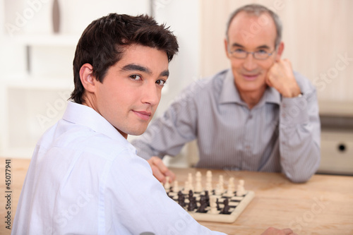 Young man playing chess with his grandfather