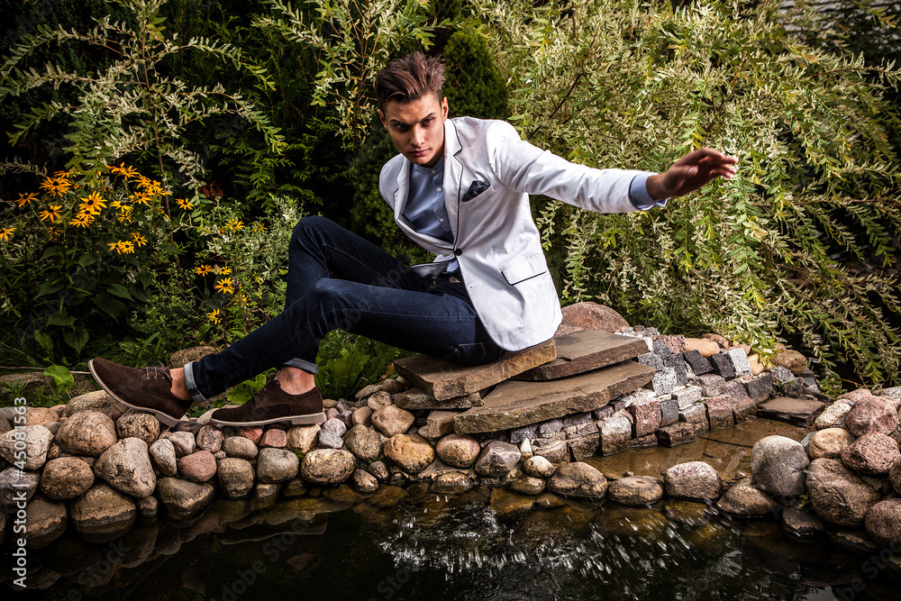 Fototapeta premium young beautiful fashionable man against autumn garden.