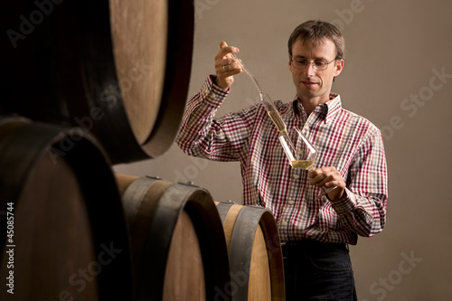 Winemaker in cellar making wine test. photo