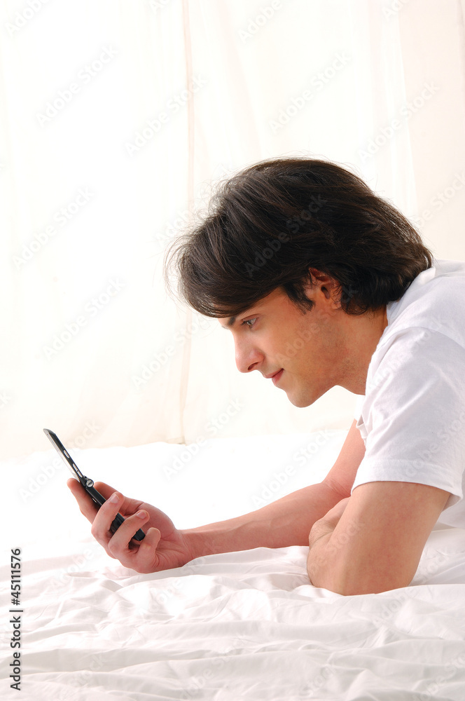 young man talking on the cell phone sitting on the bed young man talking on the cell phone sitting on the bed