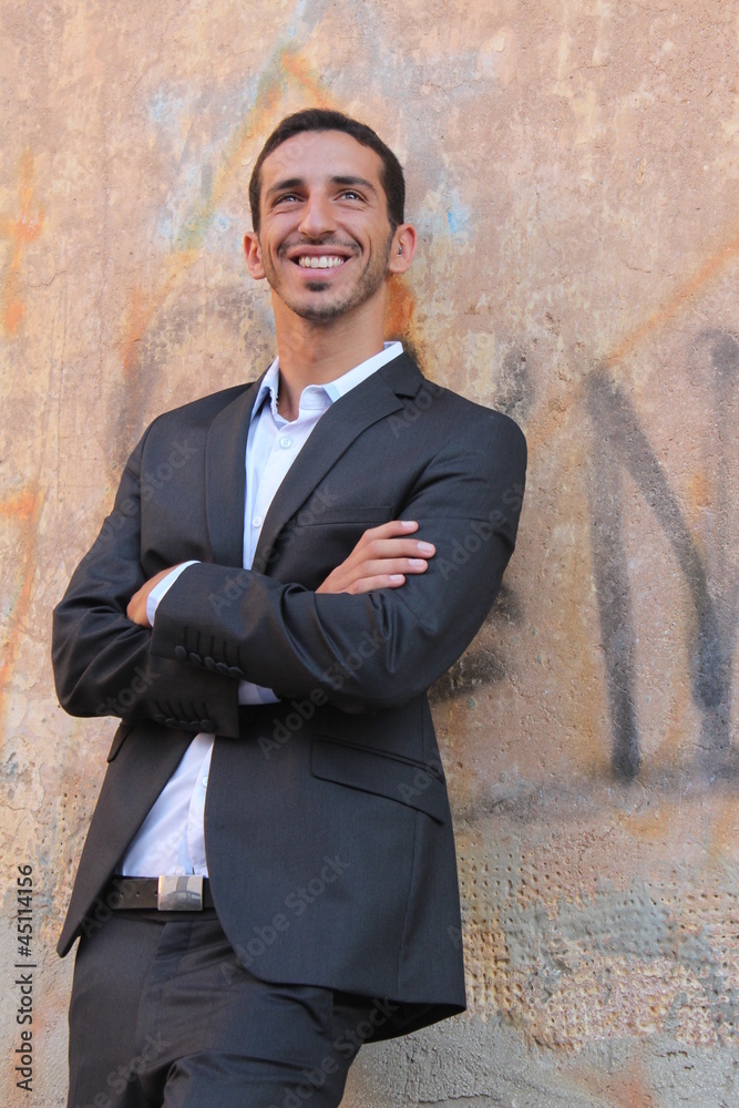 Middle-east businessman standing near a wall and smiling Middle-east businessman standing near a wall and smiling