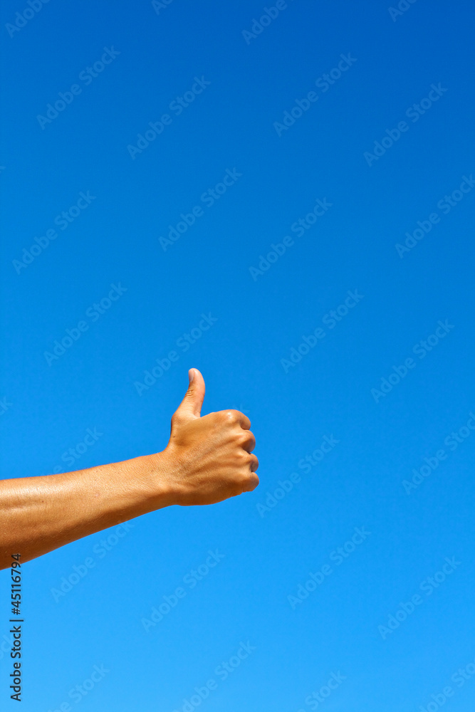 Isolated thumbs up against blue sky