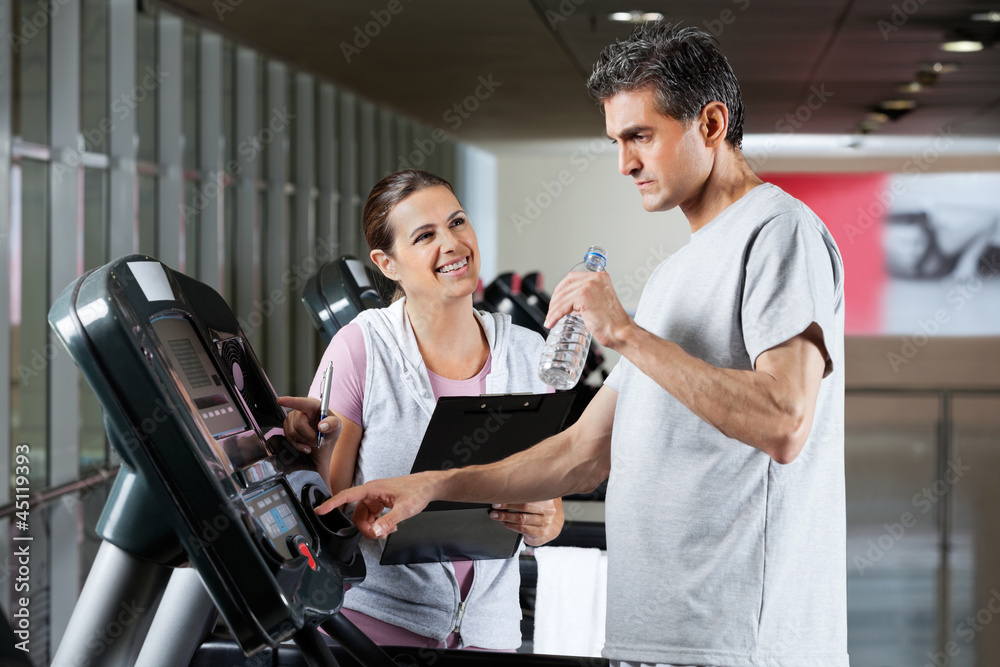 Instructor Looking At Male Client On Treadmill Instructor Looking At Male Client On Treadmill