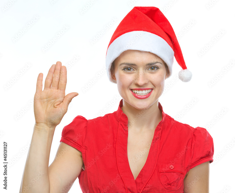 Happy young woman in Christmas hat saluting