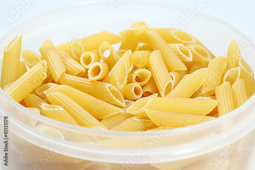 Uncooked penne pasta in plastic holder