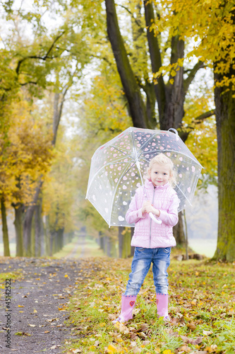 little girl with umbrella in autumnal alley