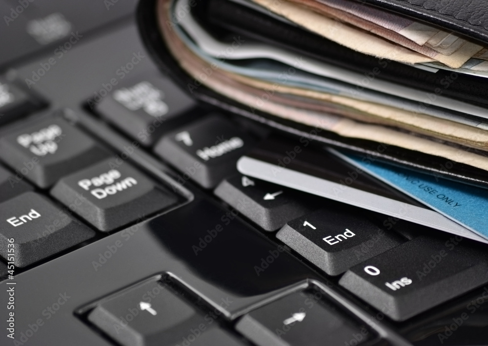 Wallet with money and bank cards on computer keyboard Wallet with money and bank cards on computer keyboard