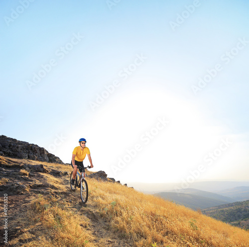 Young male riding a mountain bike on a sunset