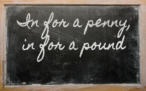 expression -  In for a penny, in for a pound - written on a scho photo