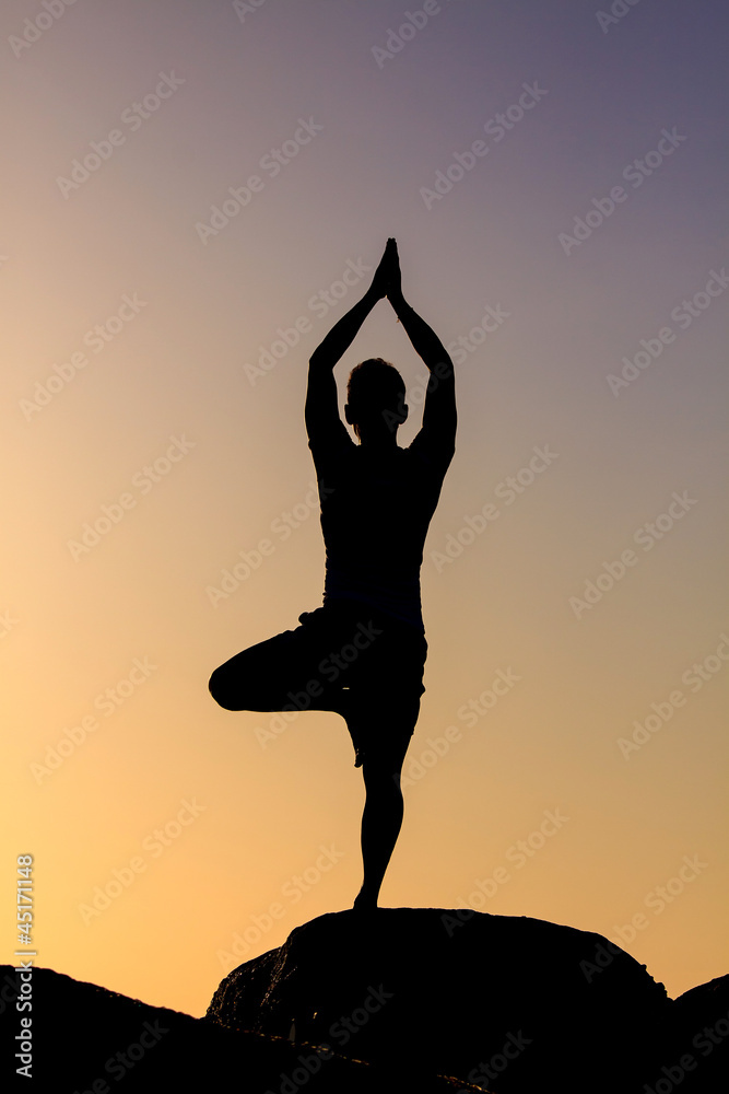 Silhouetted of asian man acts yoga on the beach in the morning