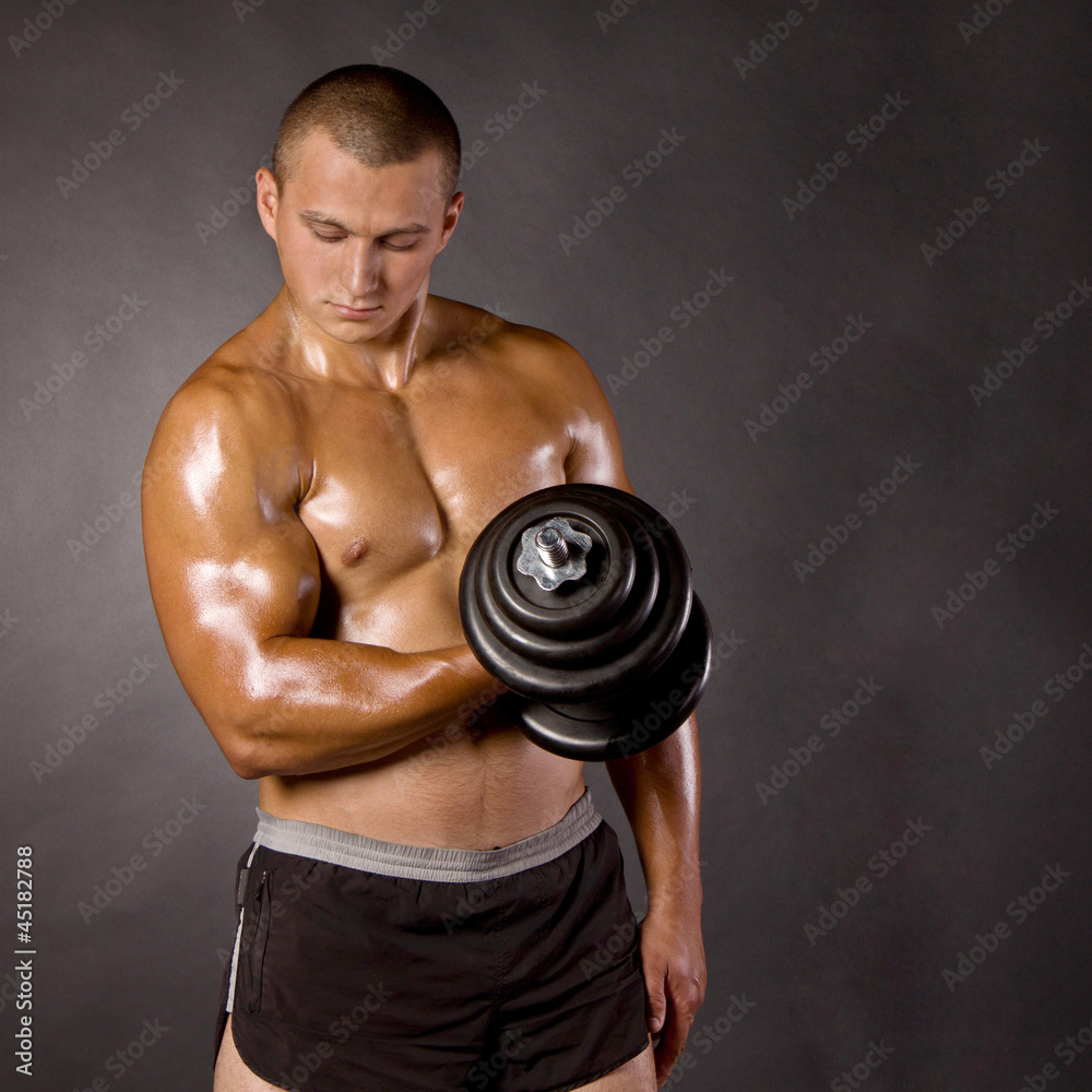 Muscled male bodybuilder dumbbell swing