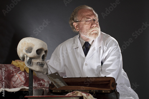 Evil doctor with surgical tools and bloody corpse photo